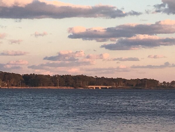 A calm body of water with a distant shoreline and a bridge.