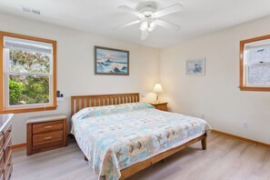 A bedroom with a wooden bed, a nightstand, a dresser, and a ceiling fan.