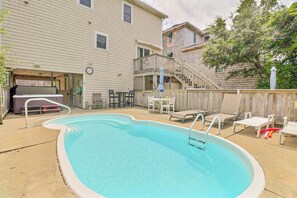 A backyard with a swimming pool, a hot tub, and outdoor furniture.