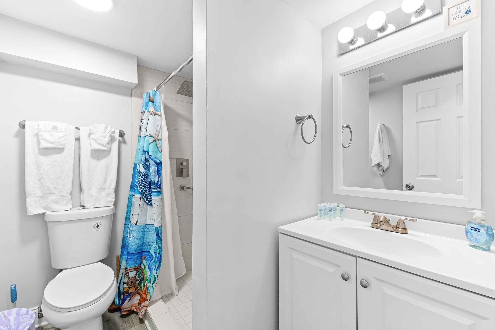 Un baño con inodoro, lavamanos con espejo y cortina de ducha.