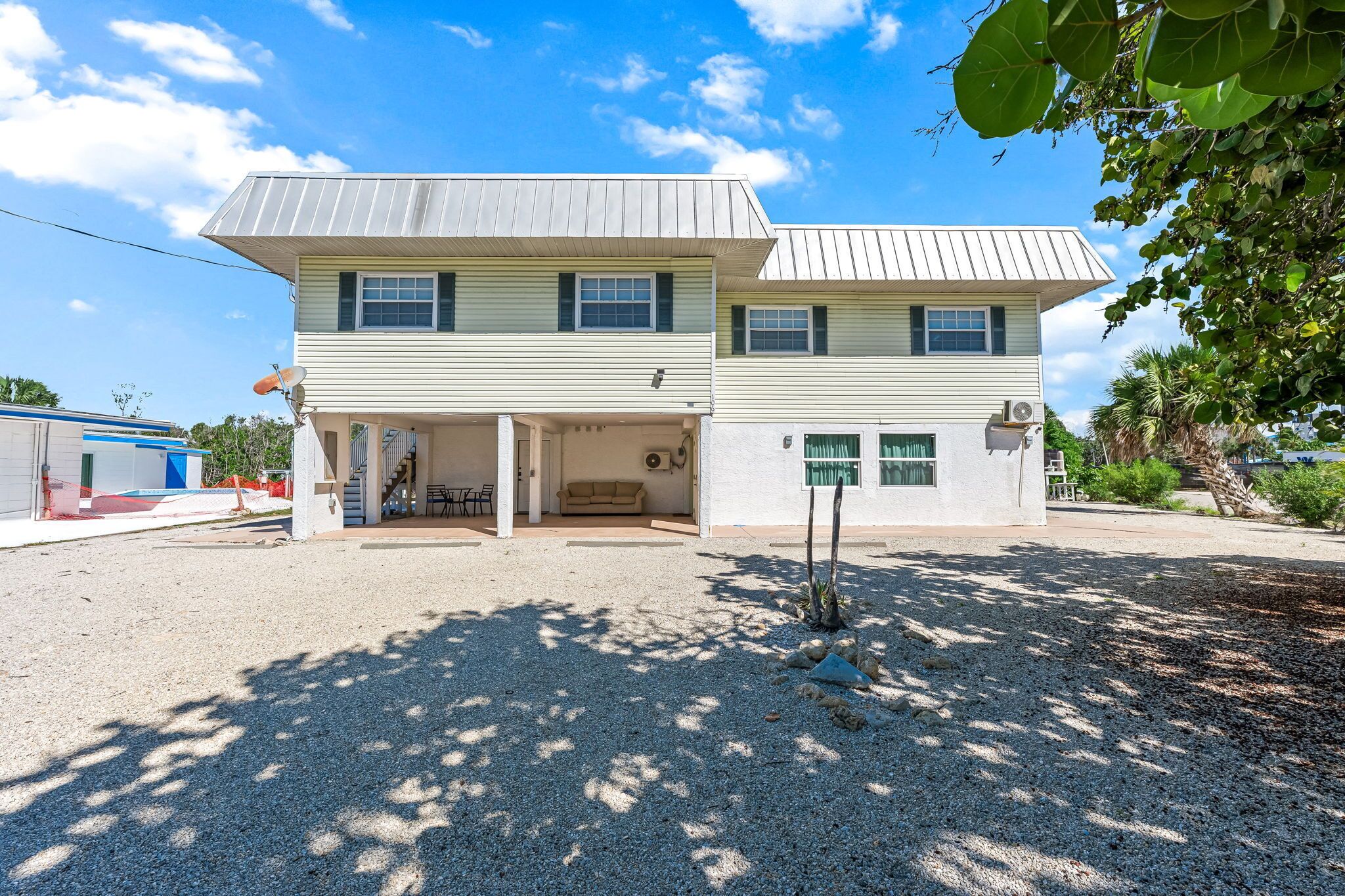 A two-story house with a front porch, a satellite dish, and a small garden area.