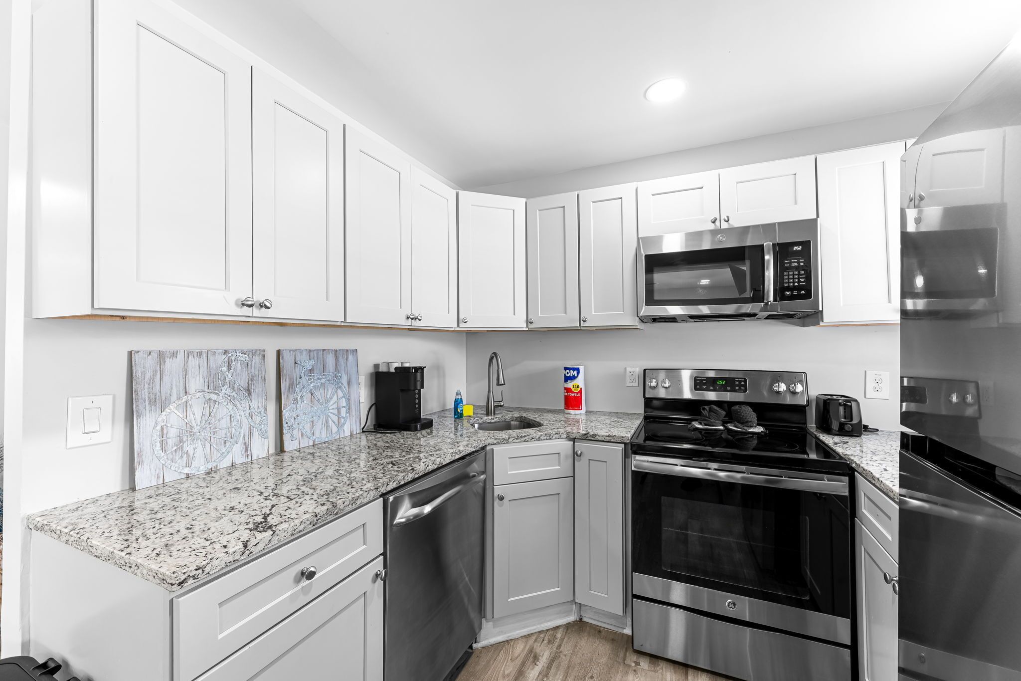A modern kitchen with white cabinets, stainless steel appliances, and a granite countertop.