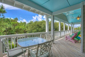 Uma área externa coberta com mesa e cadeiras, piscina e cadeiras Adirondack coloridas.