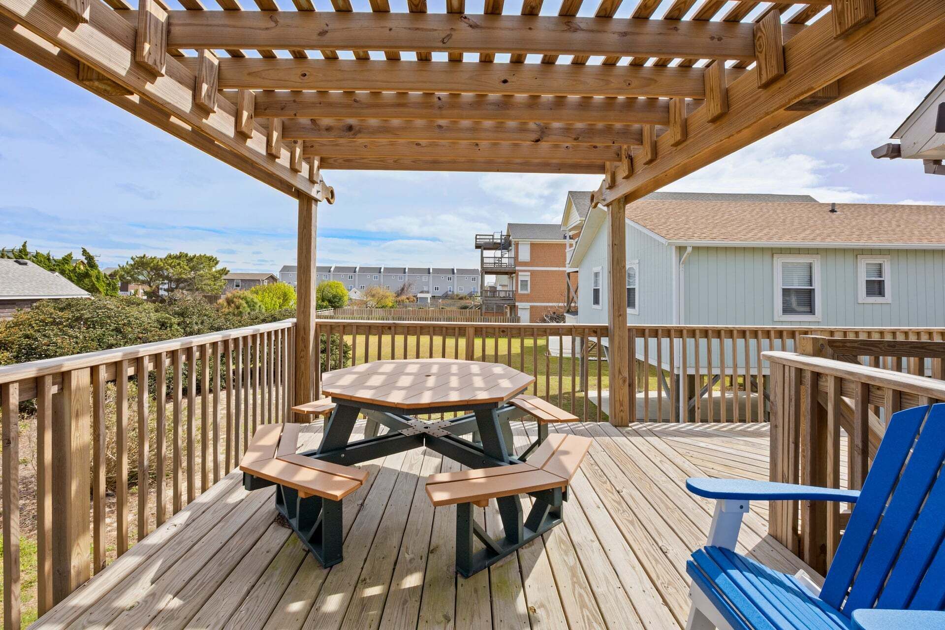 A wooden deck with a picnic table and benches, surrounded by a wooden railing.
