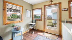 Une pièce chaleureuse avec une porte en bois, une petite table ornée d’une plante, une chaise et une vue sur l’extérieur.