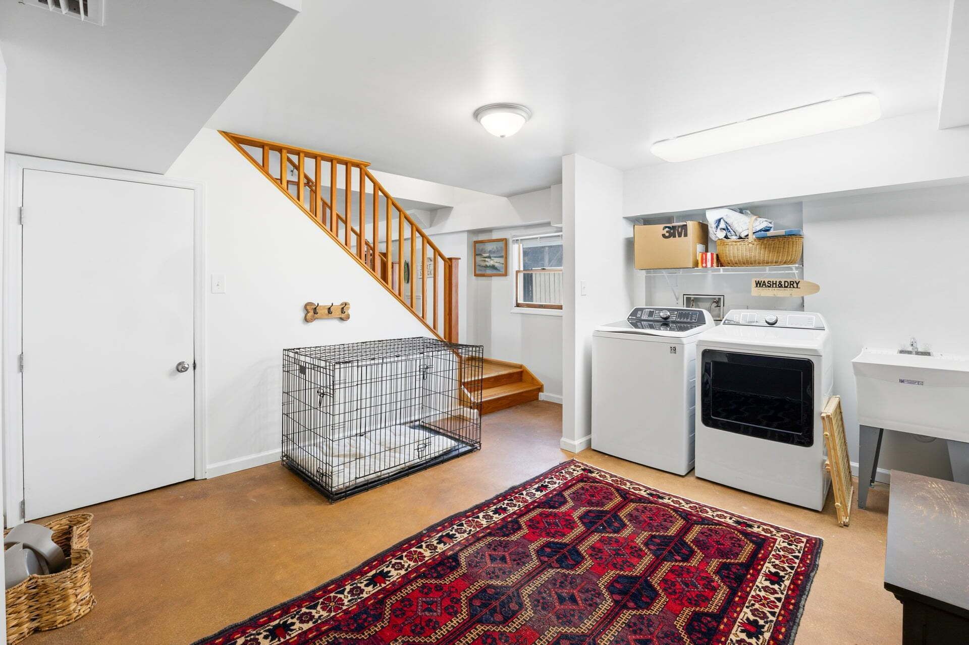 A laundry room with a washing machine, dryer, and a cage.