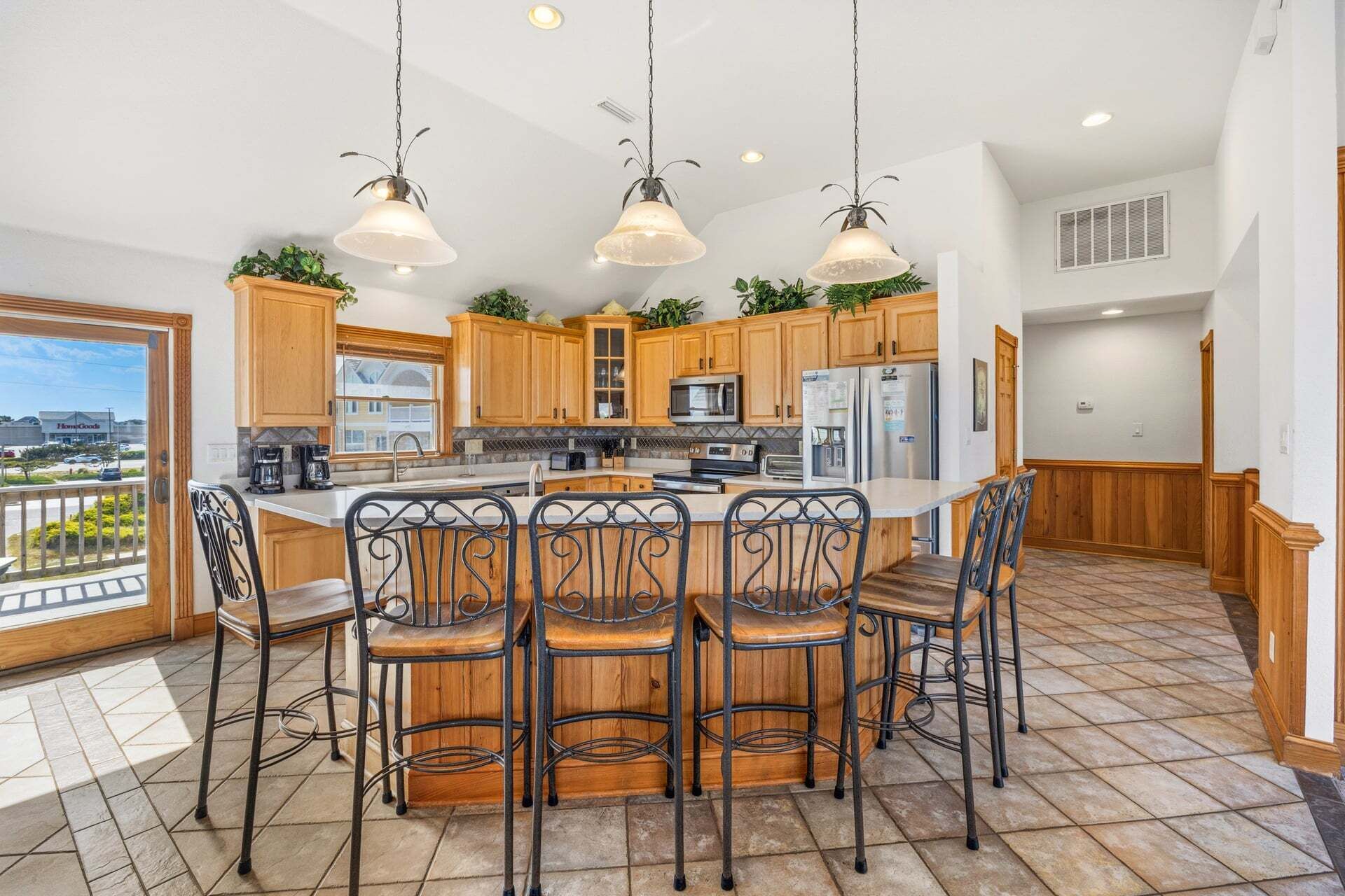 A spacious kitchen with wooden cabinets, a central island with bar stools, and pendant lighting.