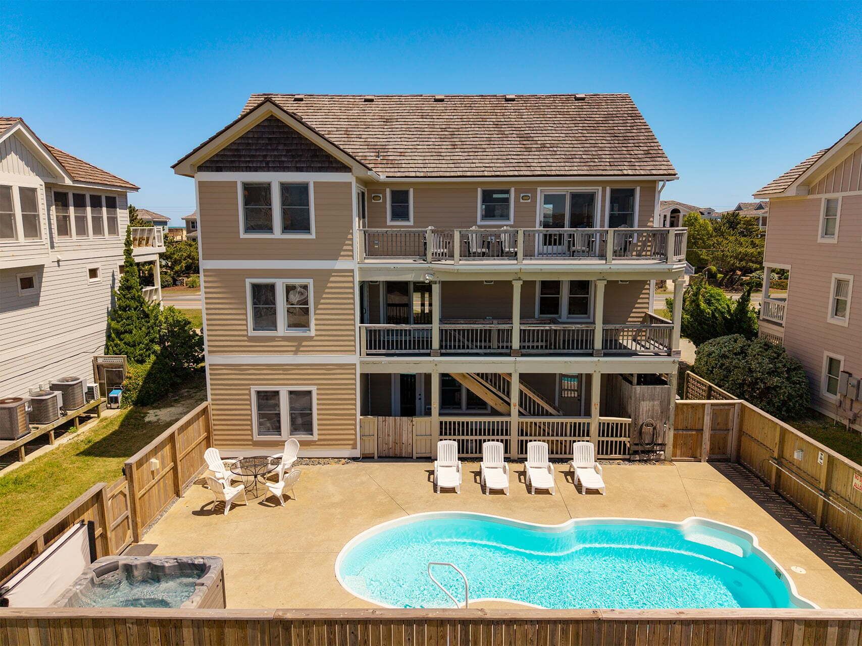 A multi-story building with a swimming pool, outdoor seating, and a wooden deck.