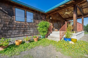 Step into this charming cabin, surrounded by lush greenery and a covered porch with a ceiling fan.