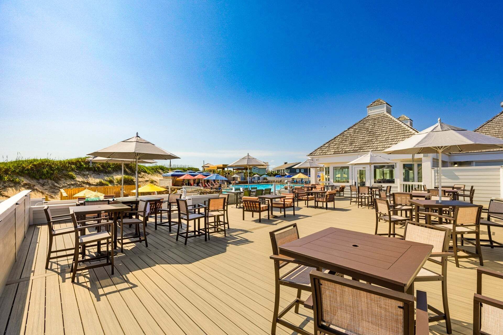 Une terrasse avec des sièges et des parasols, donnant sur un espace piscine.