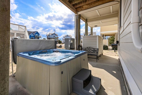 Een bubbelbad in een overdekte buitenruimte met uitzicht op huizen.