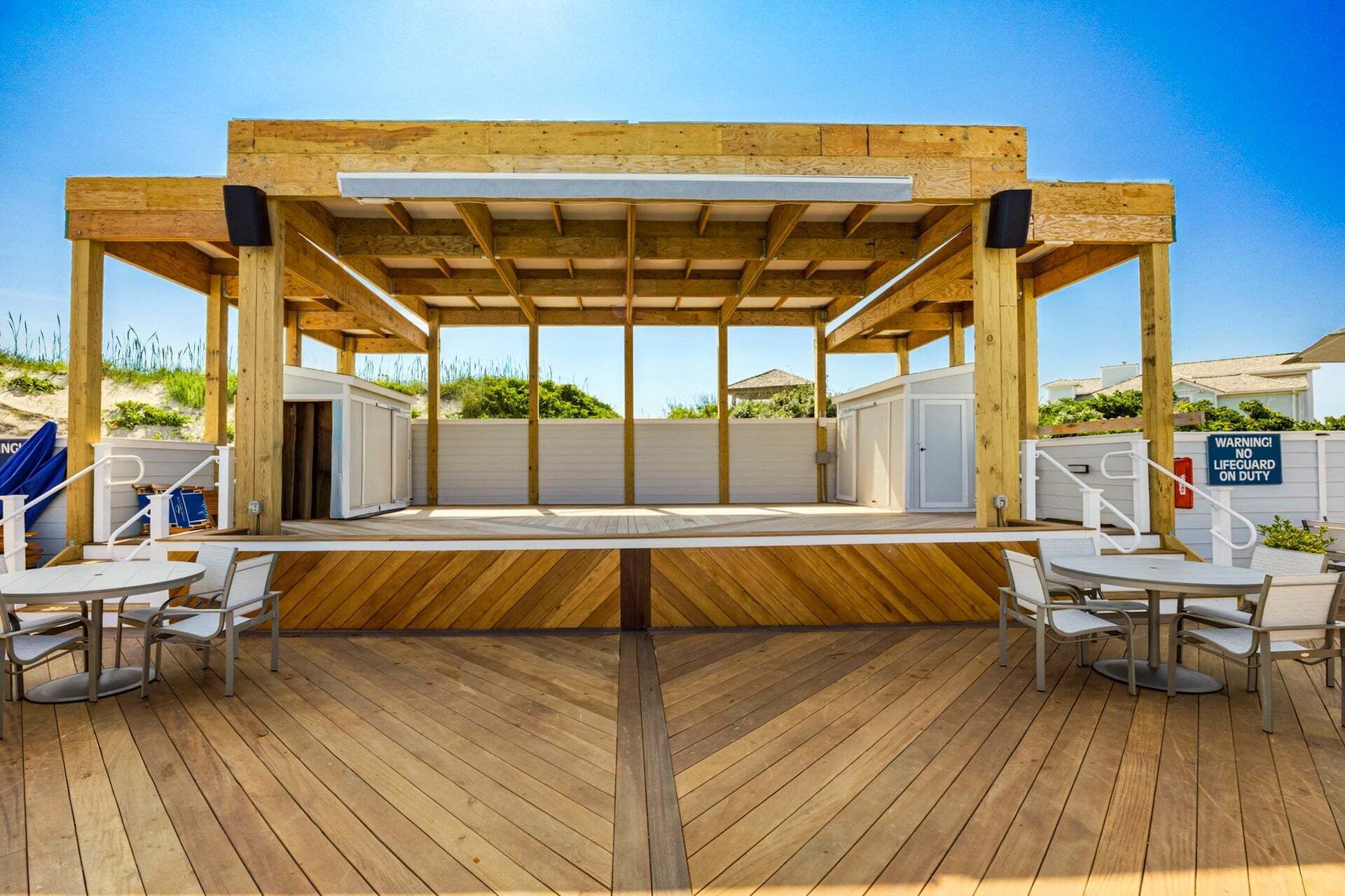 Un espace extérieur abrité, doté de tables et de chaises, d’un sol en bois et offrant une vue sur le paysage environnant.