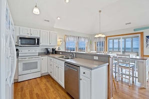 A modern kitchen with white cabinets, stainless steel appliances, and a large island with a sink.