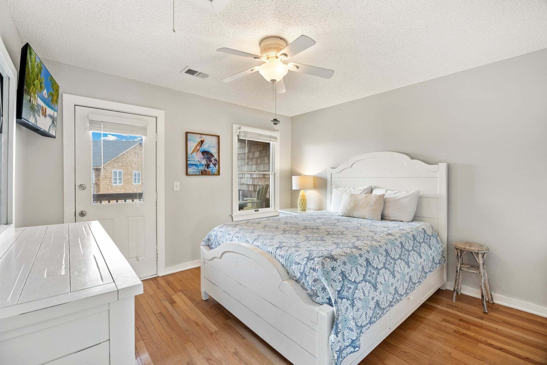 A bedroom with a bed, a desk, a ceiling fan, and a window.