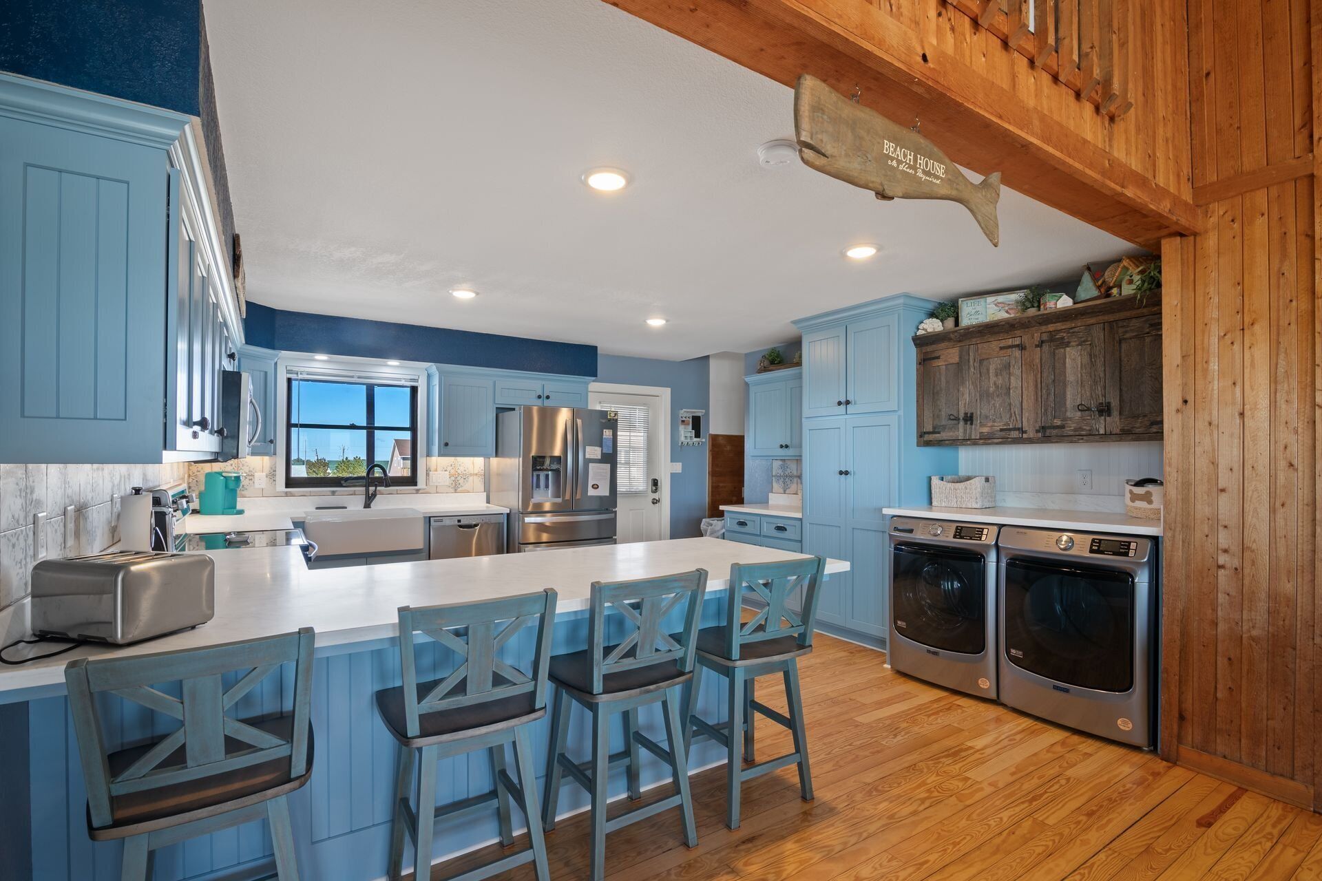 A modern kitchen with a large island, stainless steel appliances, and blue cabinetry.