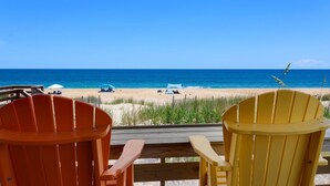 A beach view with two Adirondack chairs and a wooden deck. - 7060 Tides Times * Oceanfront * Pool * Hot Tub (Nags Head)
