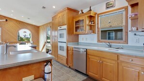 Une cuisine moderne avec des meubles en bois, des appareils en acier inoxydable et un grand îlot central doté d’un évier.
