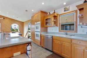 A modern kitchen with wooden cabinets, stainless steel appliances, and a large island with a sink. - 7088 Short II * 1 Min Walk to the Beach (Nags Head)