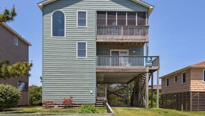 Un bâtiment à deux étages doté d’un balcon au deuxième étage, d’un petit espace de véranda et d’une enseigne publicitaire pour la location de logements de vacances.