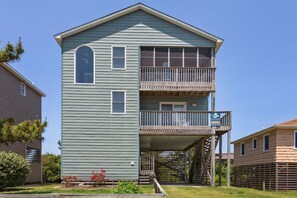 A two-story building with a balcony on the second floor, a small porch area, and a sign advertising vacation rentals. - 7088 Short II * 1 Min Walk to the Beach (Nags Head)