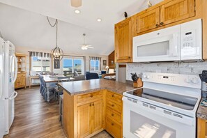 A kitchen with wooden cabinets, a microwave, an oven, and a dining area with a view.