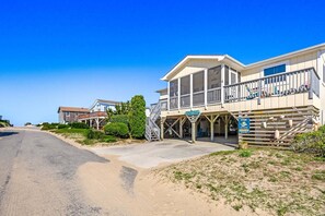 Ett hotell vid stranden med en balkong, en skylt med texten ”Semester vid havet” och en klar himmel.