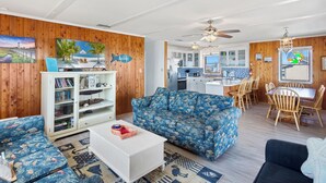 A living room with a blue patterned sofa, a white coffee table, and a bookshelf.