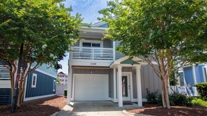 A two-story house with a white garage door, a balcony, and a mailbox. - Spacious 3BR Home | Pool, Waterpark & Near Beach (Kill Devil Hills)
