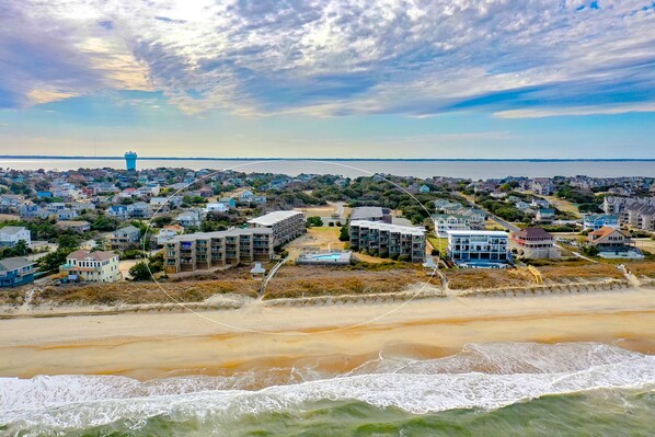 A coastal residential area with beachfront properties, a lighthouse, and a view of the sea.