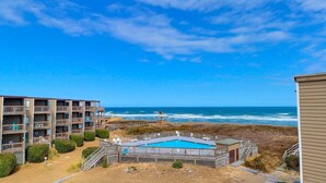 Un hotel sulla spiaggia con piscina, vista sull'oceano e numerosi balconi.