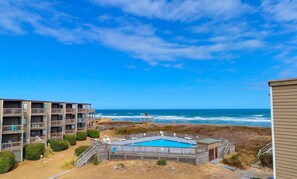 A beachfront hotel with a pool, ocean view, and multiple balconies.