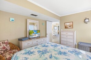 Une chambre à coucher comprenant un lit, une commode, un téléviseur et une porte donnant sur un coin repas.