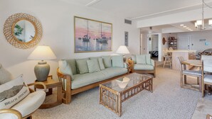 Een woonkamer met een bank, fauteuils, een salontafel en een eethoek met stoelen en een tafel.