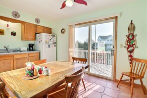 Une cuisine avec des meubles de rangement en bois, un réfrigérateur et une table à manger avec des chaises.