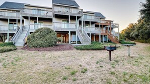 A multi-story building with balconies, a central staircase, and a well-maintained lawn. - Cozy 3-Bedroom Retreat in Duck – Walk to Beach! (Duck)
