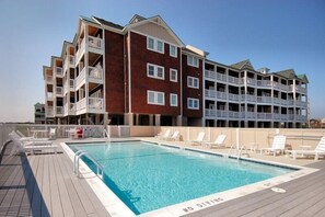 A hotel with a pool area, multiple balconies, and a brick facade.