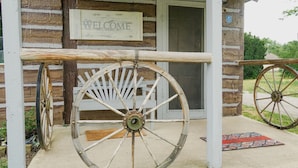 A rustic wooden structure with a 'WELCOME' sign, a wooden cart, and a door. - Wolf's Cabin Near Historic Downtown Noblesville (Noblesville)