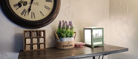 A rustic wall clock, wooden blocks, a potted plant, and a framed sign on a wooden shelf.