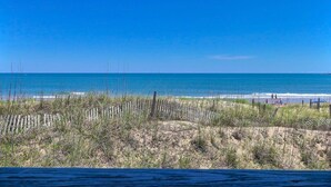 A beach with a wooden fence and sparse vegetation in the foreground.
