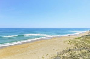 A beach with a wooden fence and dunes.