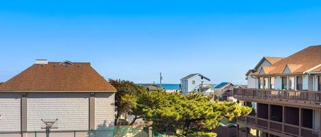 A residential area with houses, a basketball court, and a view of the ocean.