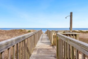 Une promenade en bois qui mène à une plage offrant une vue dégagée sur l’océan.