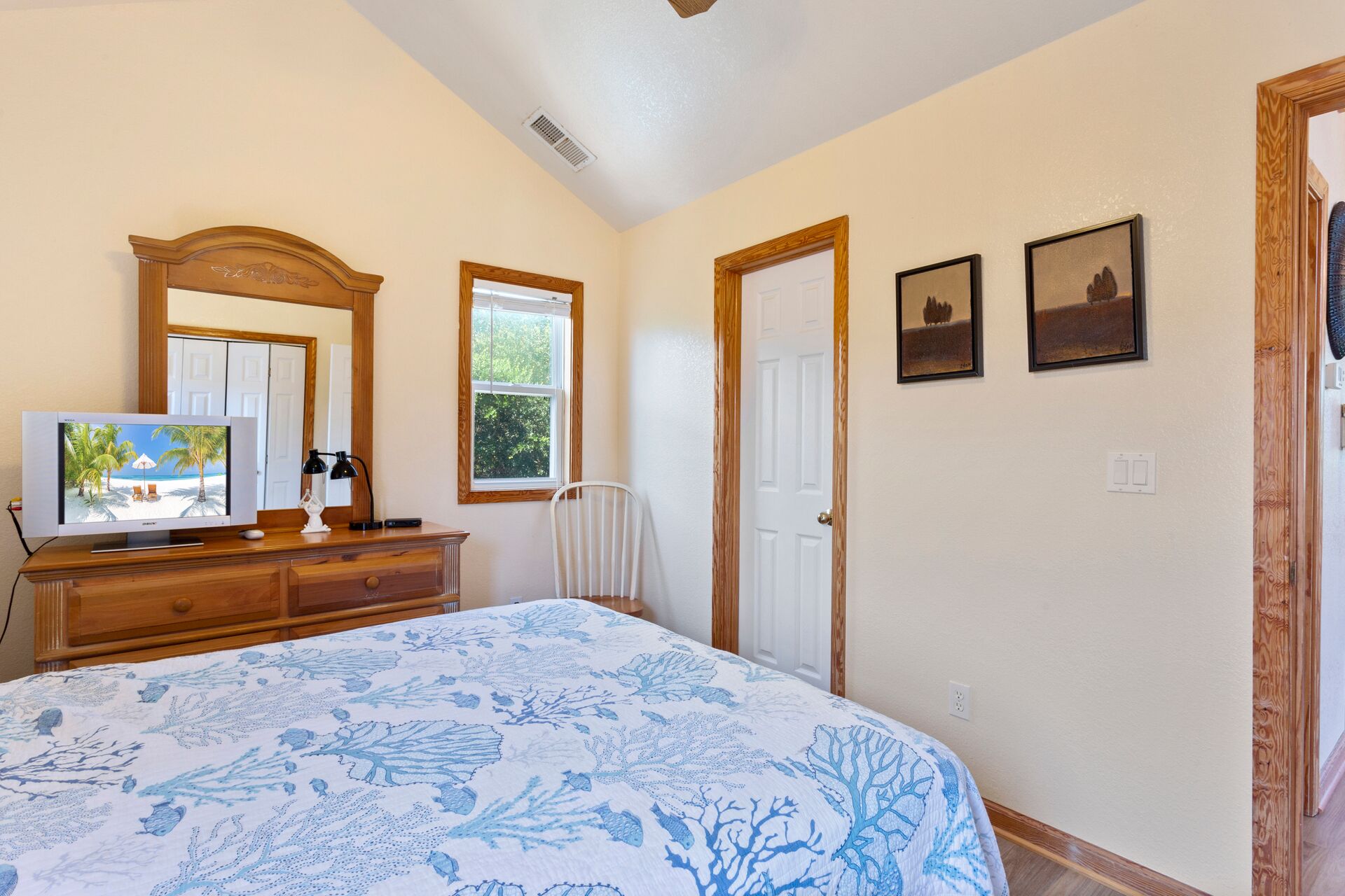 Un dormitorio con cama, cómoda, espejo y dos cuadros en la pared.