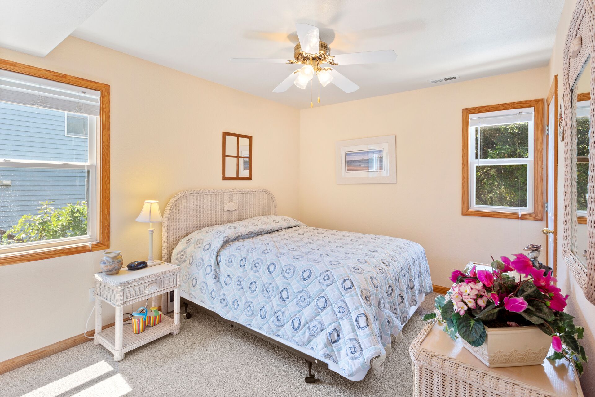 A bedroom with a bed, a nightstand, a ceiling fan, a window, and a wall-mounted picture.