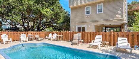 A swimming pool with lounge chairs and a wooden fence.
