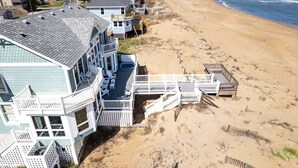 Una propiedad frente al mar con varias edificaciones, incluyendo una casa grande con balcón y una construcción más pequeña con terraza.