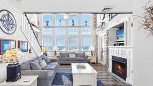 A spacious living room with a fireplace, striped sofas, a coffee table, and nautical decor.