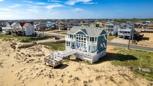 Una zona residencial costera con casas frente al mar, incluyendo una casa destacada con balcón y terraza.