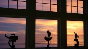 Vista a través de una ventana de múltiples paneles, cada uno mostrando un atardecer sobre el océano.