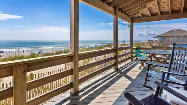 Une terrasse en bois offrant une vue sur la plage et l’océan.